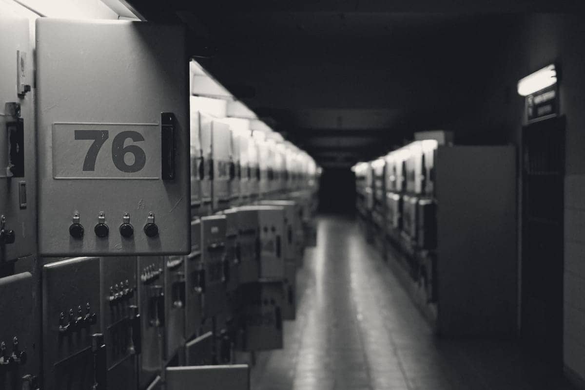A corridor lined with grey electrical switchgear cabinets, the nearest numbered 76.